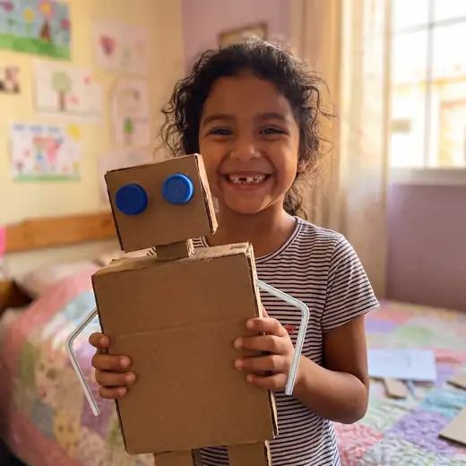 Uma menina mostra orgulhosa seu robô de papelão